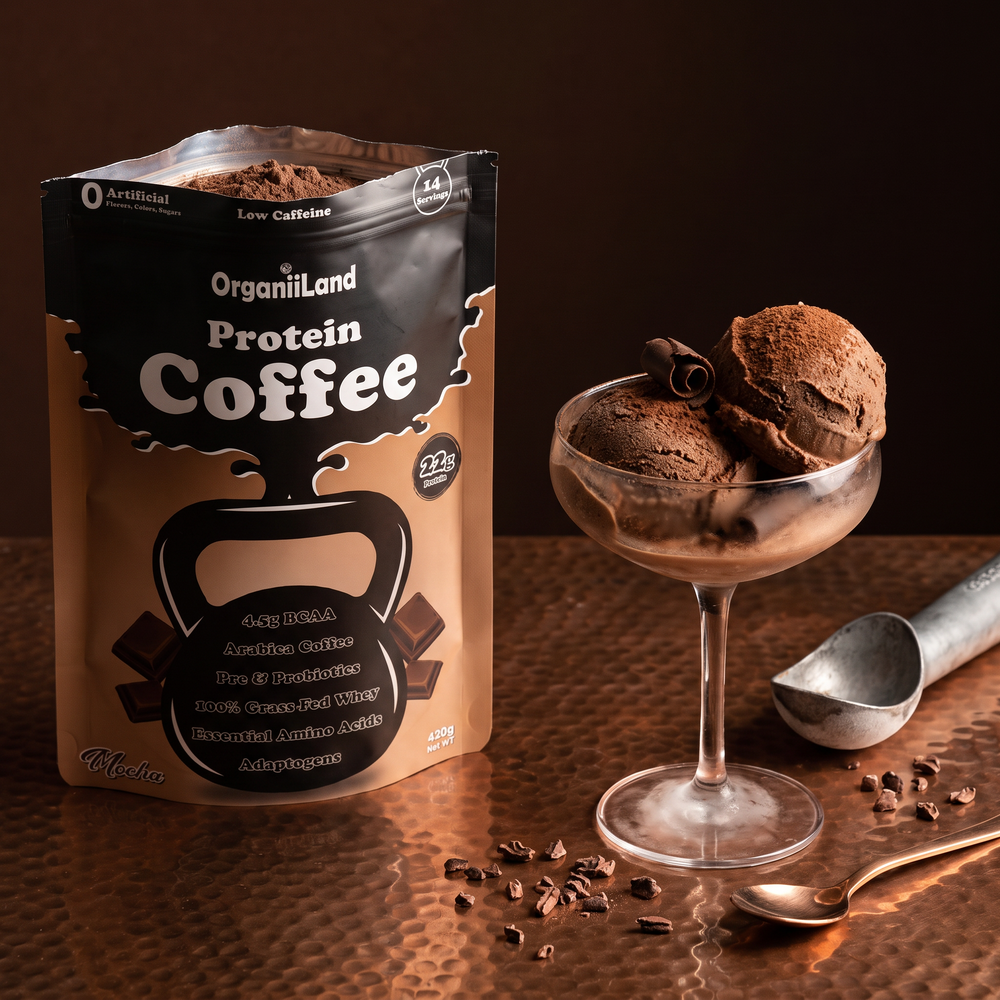 Two scoops of mocha protein ice cream in a coupe glass on copper beside an opened OrganiiLand Mocha Protein Coffee bag