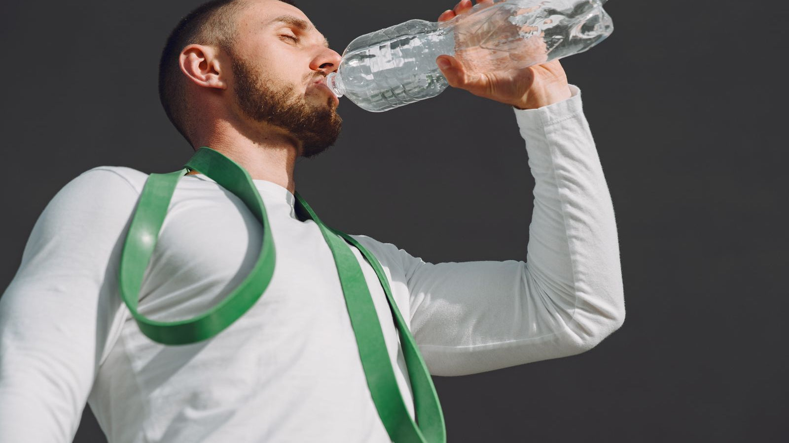 A fit man in sportswear drinking water after a workout