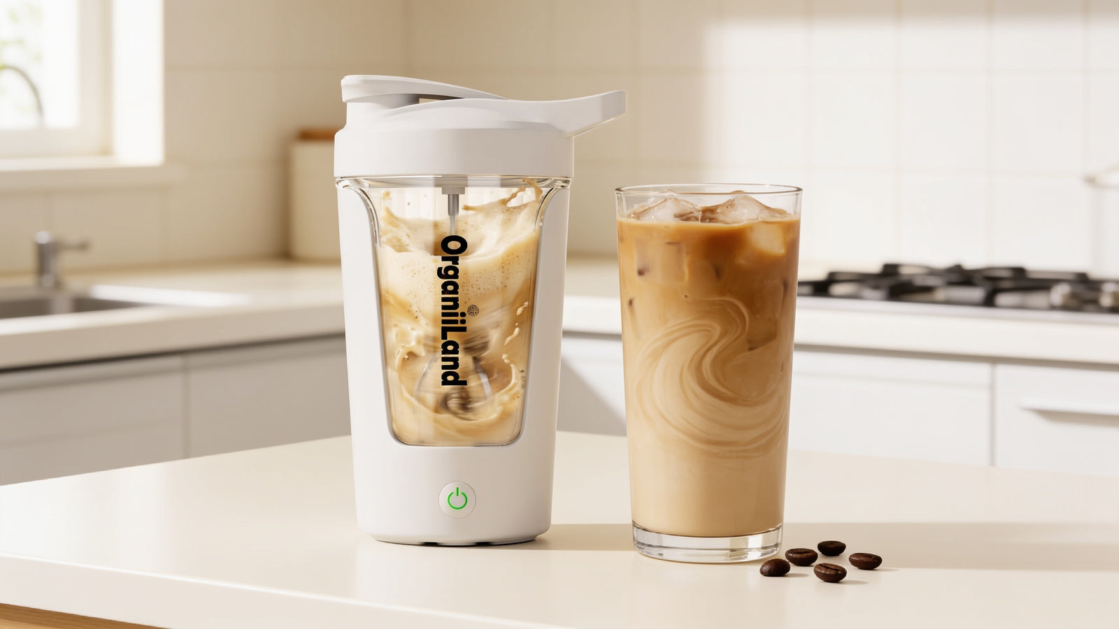 OrganiiLand electric shaker on a kitchen counter next to a tall glass of creamy iced protein coffee
