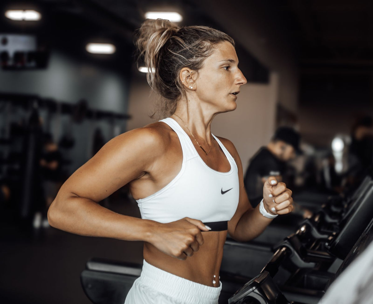 A fit woman running on a treadmill in a modern gym