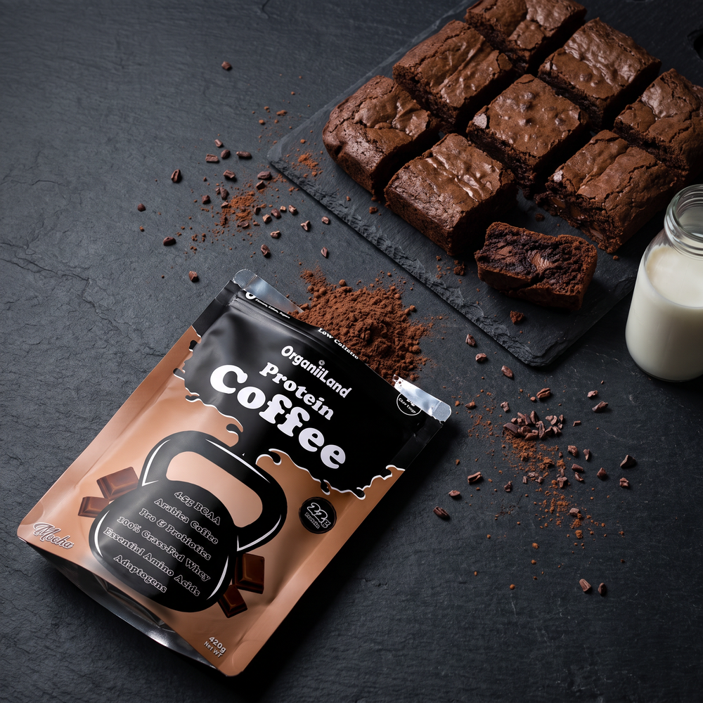 Fudgy mocha protein brownies on a slate board shot from above, with an opened OrganiiLand Mocha Protein Coffee bag lying flat beside them