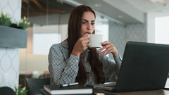 A woman sipping coffee while focused on her laptop