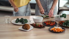 A person slicing cucumber amid a spread of fresh whole foods