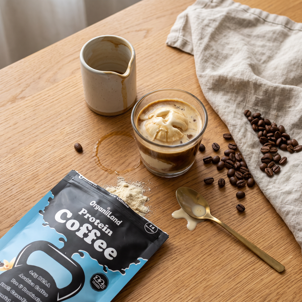 Protein affogato seen from above on an oak table, melting into dark coffee, beside an opened OrganiiLand French Vanilla Protein Coffee bag
