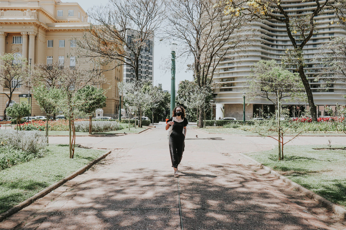 A woman walking outdoors on a sunny tree-lined path