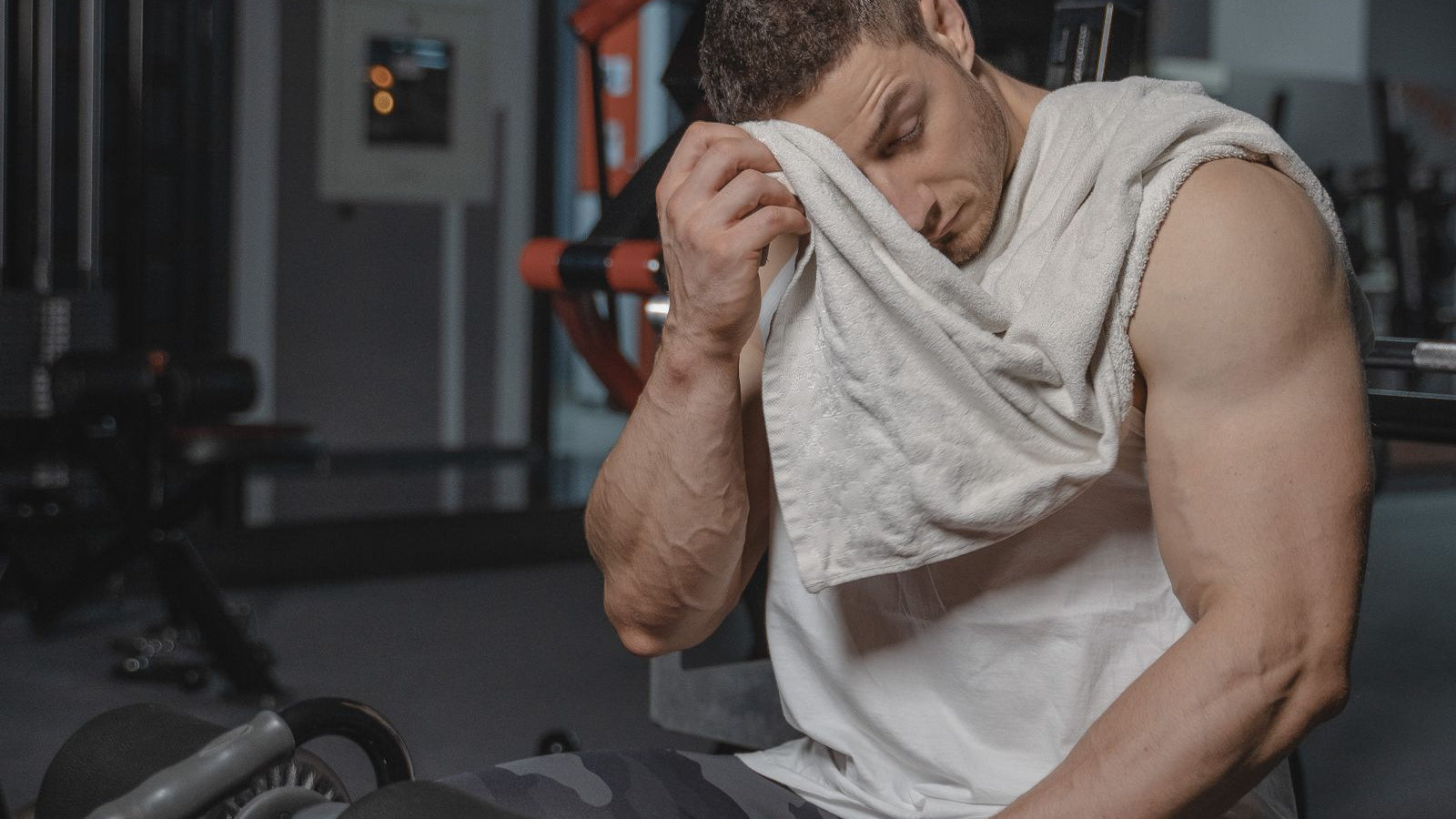 A man in a white tank top training at the gym