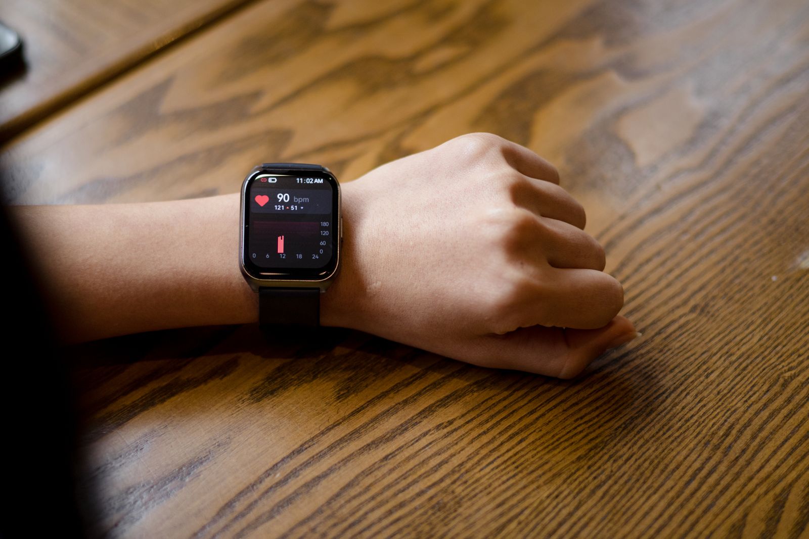 A close-up of a smartwatch on a wrist displaying a heart rate